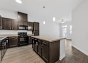Thumbnail 37 of 52 - A modern kitchen with dark wood cabinets and a central island.