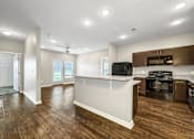 Thumbnail 22 of 32 - an open kitchen and living room with a kitchen island and wood flooring at The Barclay Apartments, Altoona, IOWA