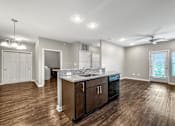 Thumbnail 23 of 32 - an empty living room with a kitchen with a counter top at The Barclay Apartments, Altoona