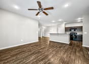 Thumbnail 26 of 32 - an empty living room with a ceiling fan and a kitchen at The Barclay Apartments, Altoona, IA, 50009