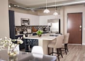 Thumbnail 2 of 34 - A kitchen with a table and chairs and a vase of flowers on the table.at Linc, Des Moines, IA 50309  