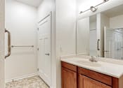 Thumbnail 33 of 35 - A bathroom with a sink, mirror, and a door at Melbourne Apartments, Georgia