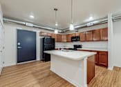 Thumbnail 31 of 35 - A kitchen with a white counter top and wooden cabinets at Melbourne Apartments, IA, 50320