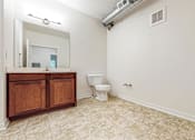 Thumbnail 25 of 35 - A bathroom with a toilet and a vanity with a mirror at Melbourne Apartments, Des Moines, Iowa