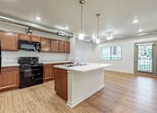 Thumbnail 20 of 35 - A kitchen with wooden cabinets and a white island at Melbourne Apartments, Des Moines