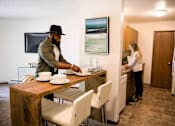 Thumbnail 6 of 90 - a man setting a table in a kitchen with a woman in the sink at Rosemont Place Apartments, Des Moines, IA