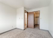 Thumbnail 33 of 90 - A room with a carpeted floor and a wooden door at Rosemont Place Apartments, Iowa, 50320