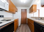 Thumbnail 32 of 90 - A kitchen with a white stove top oven and black dishwasher at Rosemont Place Apartments, Des Moines
