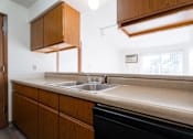 Thumbnail 28 of 90 - A kitchen with a sink and wooden cabinets at Rosemont Place Apartments, Des Moines, Iowa