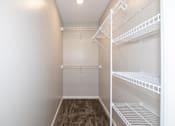 Thumbnail 10 of 90 - a spacious walk in closet with white shelves and a mirrored closet door at Rosemont Place Apartments, Iowa, 50320