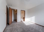 Thumbnail 26 of 90 - A room with a carpeted floor and white walls with a brown door. at Rosemont Place Apartments, Des Moines, 50320