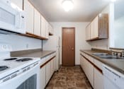 Thumbnail 38 of 90 - A kitchen with white appliances and brown cabinets at Rosemont Place Apartments, Iowa, 50320