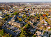 Thumbnail 87 of 90 - A large building with a parking lot in front of it is surrounded by trees and other buildings. at Rosemont Place Apartments, Des Moines, Iowa