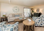 Thumbnail 7 of 90 - A living room with a clock on the wall and a couch with a pillow on it at Rosemont Place Apartments, Des Moines