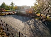 Thumbnail 44 of 90 - A parking lot with a fence and trees in the background. at Rosemont Place Apartments, Iowa