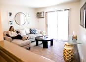 Thumbnail 1 of 90 - a woman sitting on a couch reading a book in a living room at Rosemont Place Apartments, Iowa, 50320