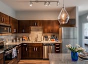 Thumbnail 9 of 30 - a kitchen with wooden cabinets and stainless steel appliances at Soll, Des Moines  
