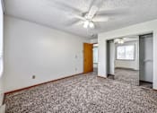 Thumbnail 14 of 21 - an empty living room with a ceiling fan and a refrigerator at Somerset Apartments, Des Moines