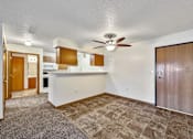Thumbnail 16 of 21 - an empty living room with a kitchen and a ceiling fan at Somerset Apartments, Iowa, 50315