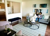 Thumbnail 7 of 26 - two people sitting on a couch in a living room at Sutton Hill Apartments, Des Moines, IOWA