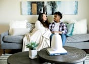 Thumbnail 4 of 26 - a couple sitting on a couch in a living room at Sutton Hill Apartments, Des Moines