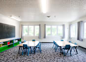 Thumbnail 25 of 26 - a classroom with tables and chairs and a chalkboard on the wall at Sutton Hill Apartments, Des Moines, IA, 50320