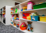 Thumbnail 17 of 26 - A white shelving unit with toys and containers on it at Sutton Hill Apartments, Des Moines, IOWA