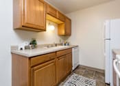 Thumbnail 8 of 26 - A kitchen with wooden cabinets and a white fridge at Sutton Hill Apartments, Des Moines, IA, 50320