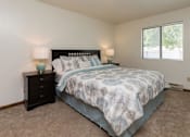 Thumbnail 10 of 26 - A bedroom with a bed, nightstand, and two lamps at Sutton Hill Apartments, Des Moines, 50320