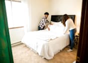 Thumbnail 9 of 26 - two people making a bed in a bedroom at Sutton Hill Apartments, Des Moines, IOWA