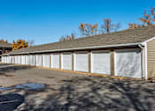 Thumbnail 15 of 26 - A long building with a grey roof and white garage doors at Sutton Hill Apartments, Des Moines, IA
