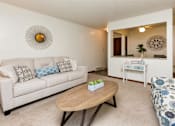 Thumbnail 3 of 26 - A living room with a couch, coffee table, and mirror at Sutton Hill Apartments, IOWA, 50320