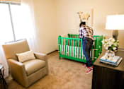 Thumbnail 11 of 26 - a baby in a room with a crib and a rocking chair at Sutton Hill Apartments, Des Moines, IA, 50320