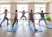 Thumbnail 29 of 40 - a group of people practicing yoga on yoga mats in a yoga studio at Velocity Apartments, Des Moines, IA