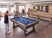 Thumbnail 31 of 40 - A group of people playing pool in a room with a pool table at Velocity Apartments, Des Moines, Iowa