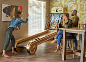 Thumbnail 32 of 40 - A woman is playing a game on a wooden board with a man and a woman watching at Velocity Apartments, Iowa