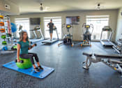 Thumbnail 30 of 40 - a woman on a stability ball in a gym with other exercise equipment at Velocity Apartments, Des Moines