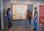 Thumbnail 34 of 40 - Three people are playing a Scrabble game in a room at Velocity Apartments, Des Moines, IA, 50309