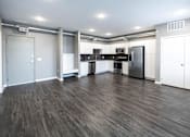 Thumbnail 7 of 40 - an empty living room with a refrigerator and a sink at Velocity Apartments, Des Moines