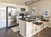 Thumbnail 5 of 40 - A kitchen with a refrigerator, microwave, and bar stools at Velocity Apartments, Des Moines, IA, 50309