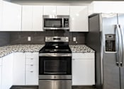 Thumbnail 8 of 40 - a kitchen with white cabinets and stainless steel appliances at Velocity Apartments, IA, 50309