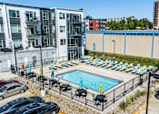 Thumbnail 22 of 40 - a swimming pool at an apartment complex with cars parked around it at Velocity Apartments, Des Moines, IA, 50309