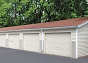 Thumbnail 14 of 20 - a white garage with white doors and a red roof at Foxwood Apartments, Indianola, IA 50125  