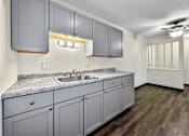 Thumbnail 7 of 20 - an empty kitchen with white cabinets and a sink at Foxwood Apartments, Indianola, IA  