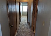 Thumbnail 12 of 24 - a hallway with wooden doors and a carpeted floor at Hunters Run Apartments, Newton, Iowa