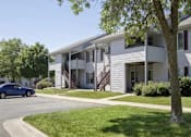 Thumbnail 23 of 24 - a white apartment building with a blue car parked in front at Hunters Run Apartments, Newton, IA,  50208