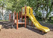 Thumbnail 16 of 24 - a playground with a slide and chairs in a park at Hunters Run Apartments, Newton, IA
