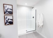 Thumbnail 35 of 99 - A white bathroom with a glass shower door and two framed pictures on the wall.at Plant 1 Lofts, N. Newton Iowa   