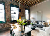 Thumbnail 38 of 99 - A dining room with a table set for two and a couch with a grey throw.at Plant 1 Lofts, Iowa, 50208
