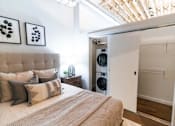 Thumbnail 40 of 99 - A bedroom with a bed, pillows, and a washing machine in the closet.at Plant 1 Lofts, N. Newton, IA 50208  